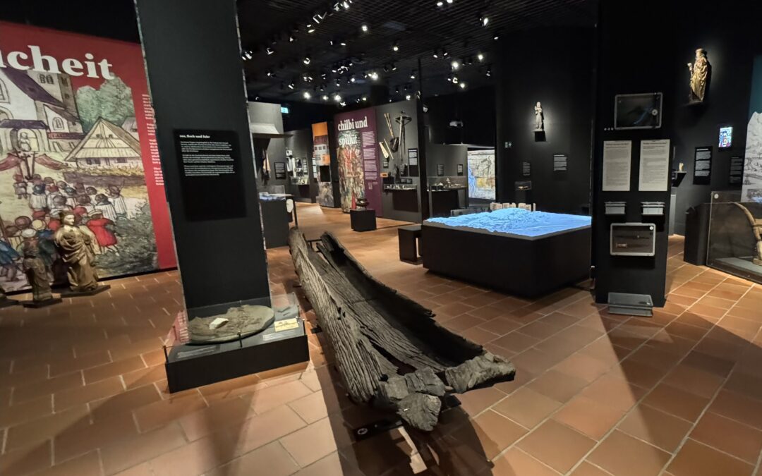 Ein Ausstellungsraum mit diversen Objekten sowie Stellwänden mit Erklärungstexten